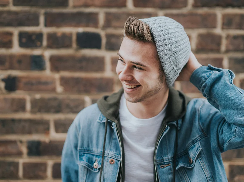 Young man with beanie and jean jacket smiling