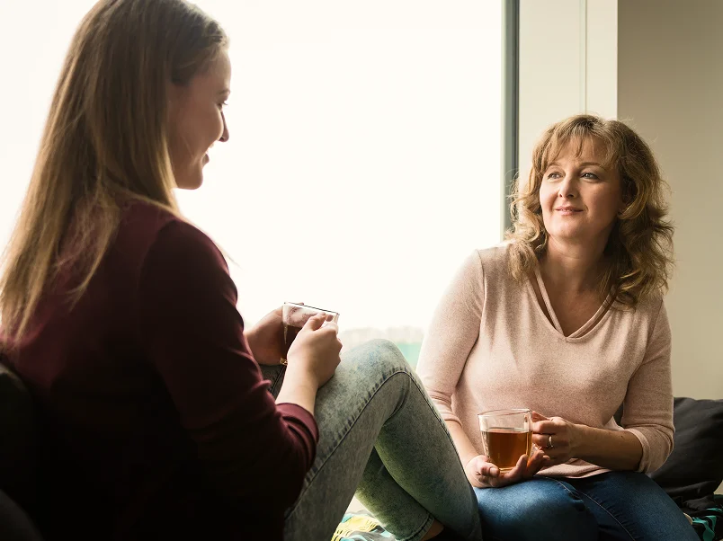 Two women talking holding tea cups